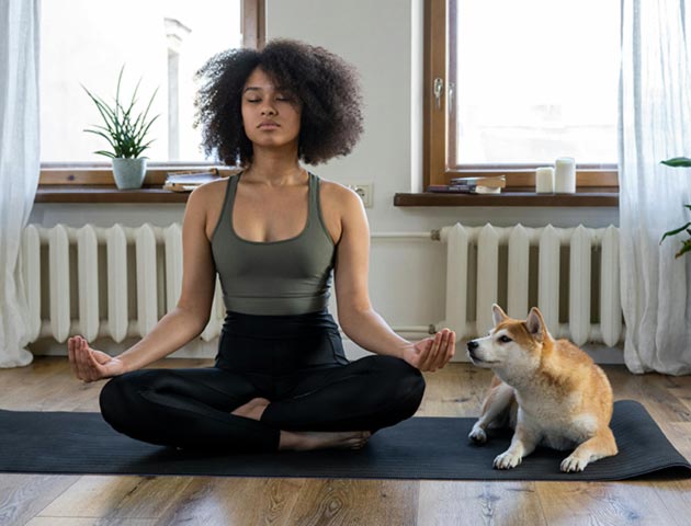 A woman meditating beside her dog (Photo: cottonbro studio on Pexels) 